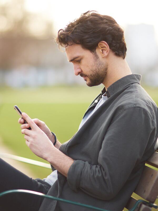 Man in a park looking through phone