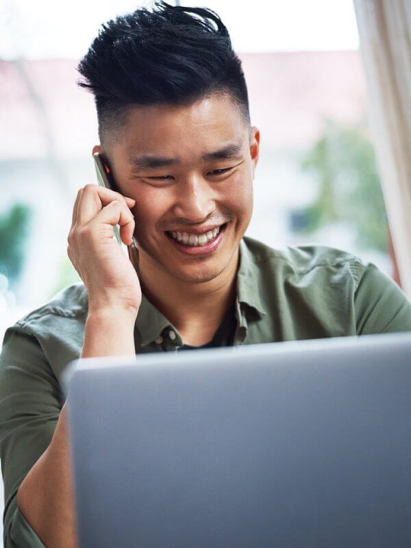 Man talking on the phone and using his laptop