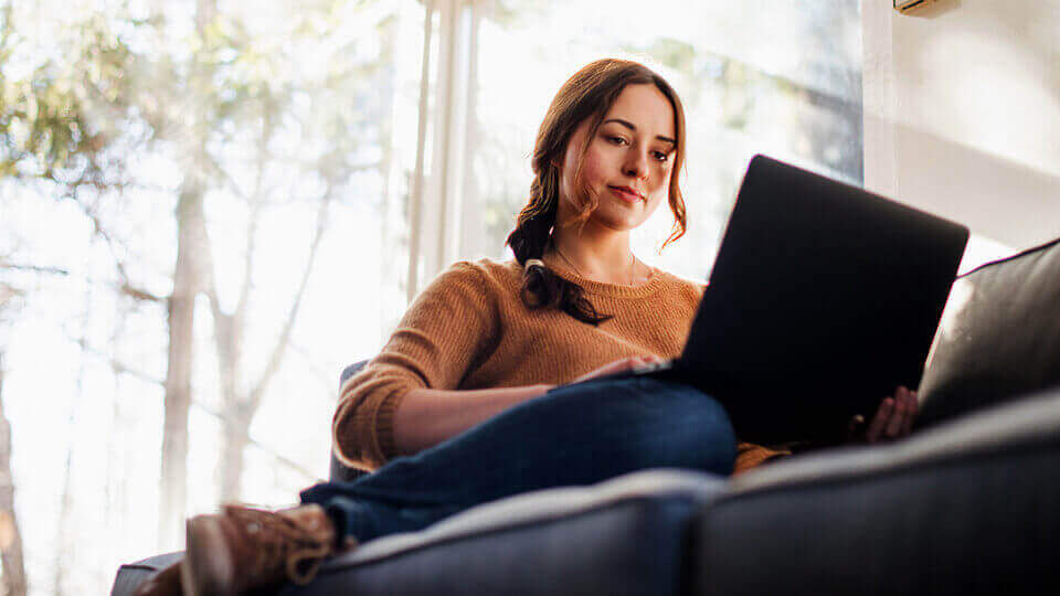 a woman sat on a sofa on her laptop